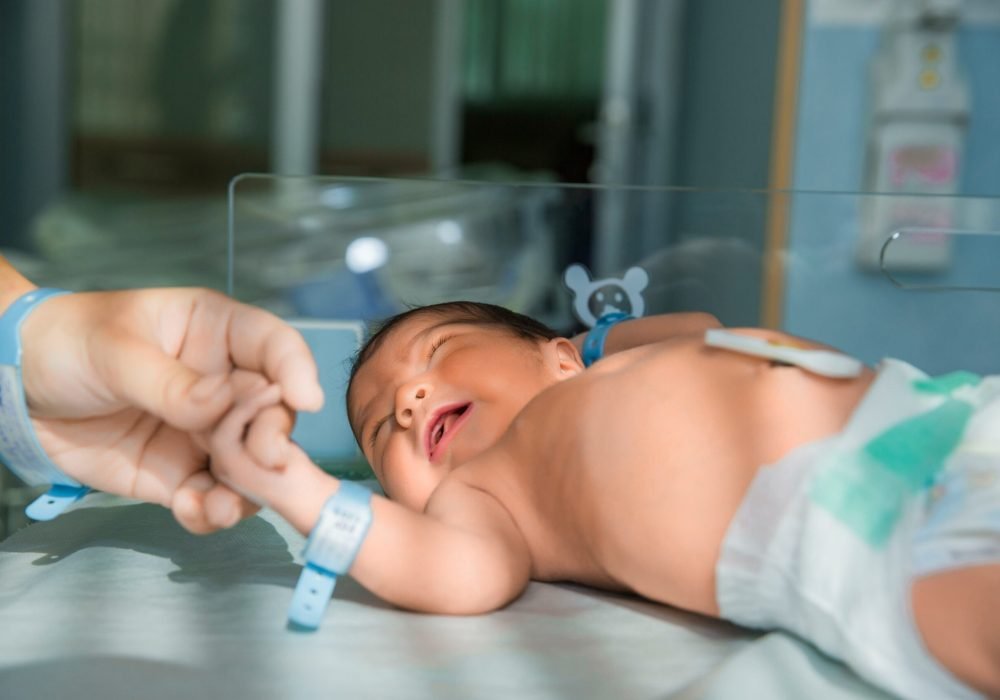 father holds hand of newly born babe in diapers