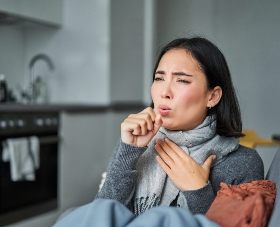 Sick korean woman coughing and feeling unwell, grimacing, has influenza, cought cold or flu, staying at home.
