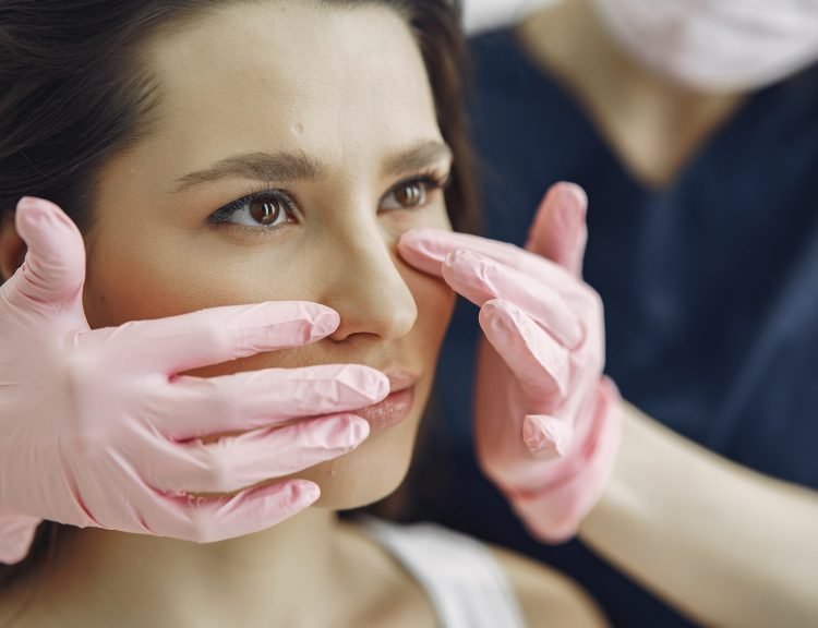 Cosmetologist holds hands near client's face. Woman with cosmetologist. Lady in a beauty studio.